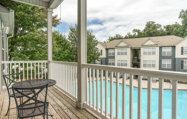 A pool is behind a white fence and a house.