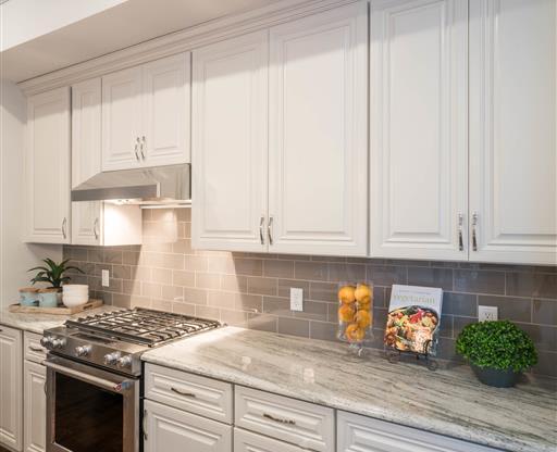 A kitchen with light countertops, subway tile backsplash, and decor accents.