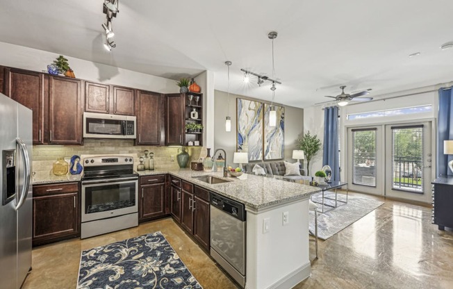 Kitchen view showing a spacious layout with dark wood cabinets and pendant lighting at Allusion at West University apartments in Houston, TX