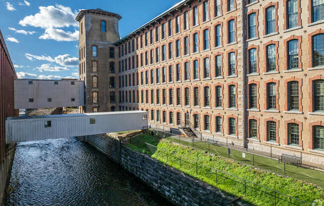 A bridge over a canal in front of a red brick building.