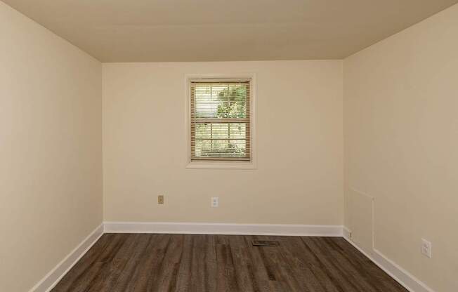 A room with a window and wooden flooring.