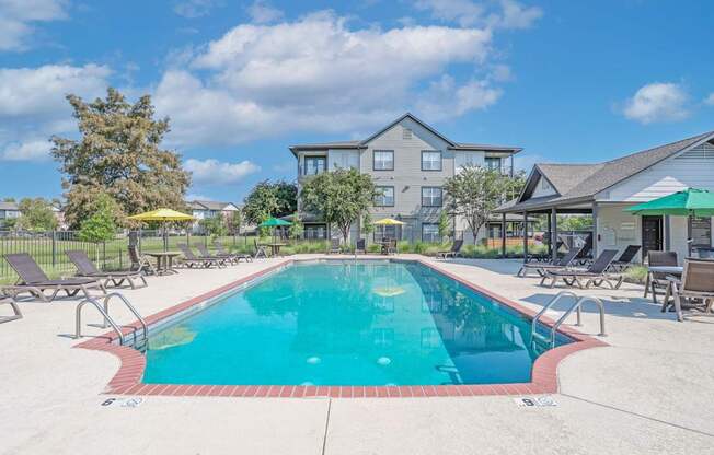 A large swimming pool surrounded by lounge chairs and umbrellas at Ultris Island Park in Shreveport, LA