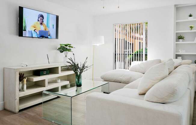 A modern living room with a white couch and a television mounted on the wall.