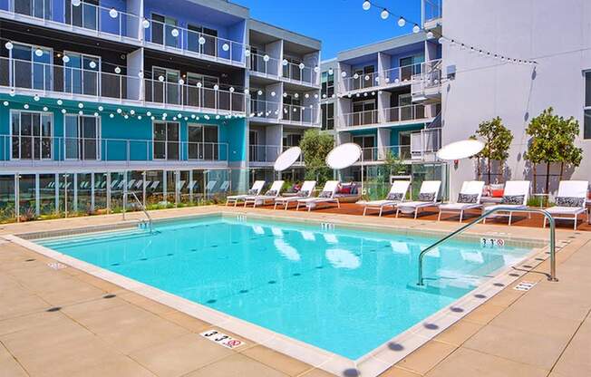 A large swimming pool in front of a multi-story apartment building.