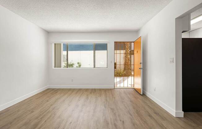 A room with a wooden floor and a door leading to a balcony.