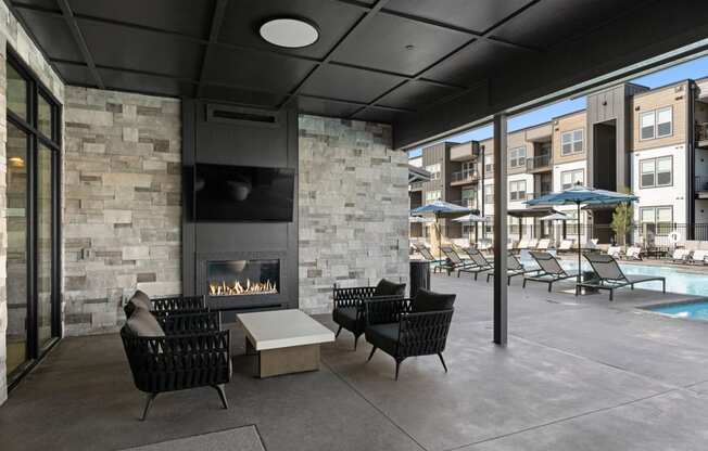 a patio with chairs and a fireplace and a pool with umbrellas