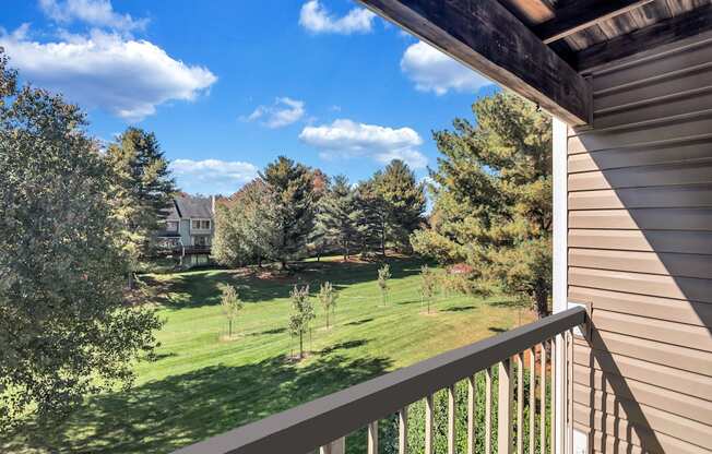 the view from the balcony of a house overlooking a yard and trees