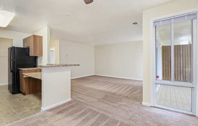 an empty living room and kitchen with a sliding glass door