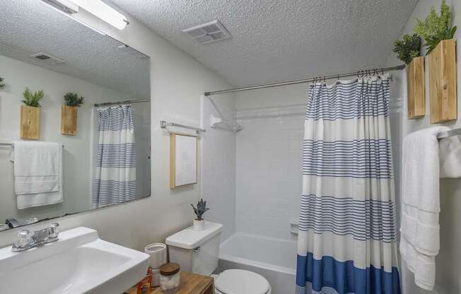 A bathroom with a white sink, toilet, and a blue and white striped shower curtain.