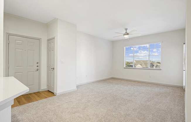 an empty living room with white walls and a ceiling fan