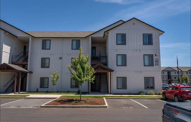 A white apartment building with a red car parked in front at Northplace Apartment Homes, Salem, 97305