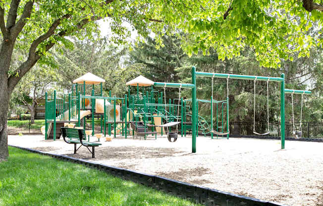 A playground with a green swing set and a yellow slide.