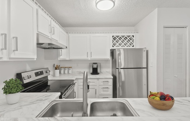 a white kitchen with stainless steel appliances and white cabinets