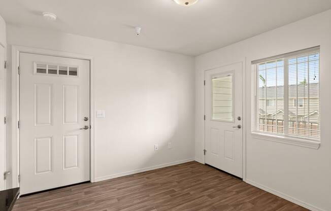 the living room of an empty home with white walls and wood flooring