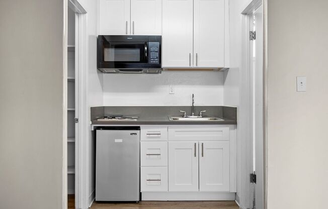a small kitchen with white cabinets and a stainless steel dishwasher