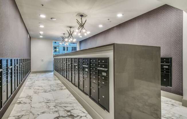 A long hallway with a marble floor and a wall of elevators.