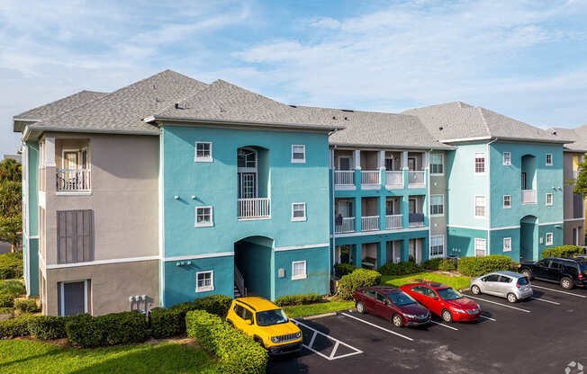 A yellow car is parked in front of a blue and beige building.
