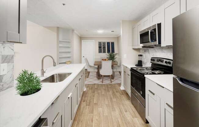 an open kitchen and living room with white cabinets and stainless steel appliances