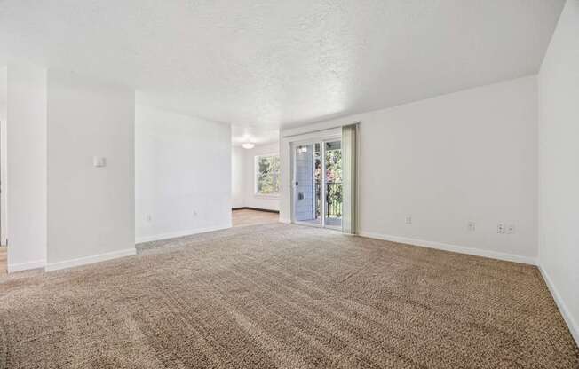 A large, empty room with a carpeted floor and white walls.