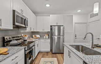 a kitchen with white cabinets and stainless steel appliances