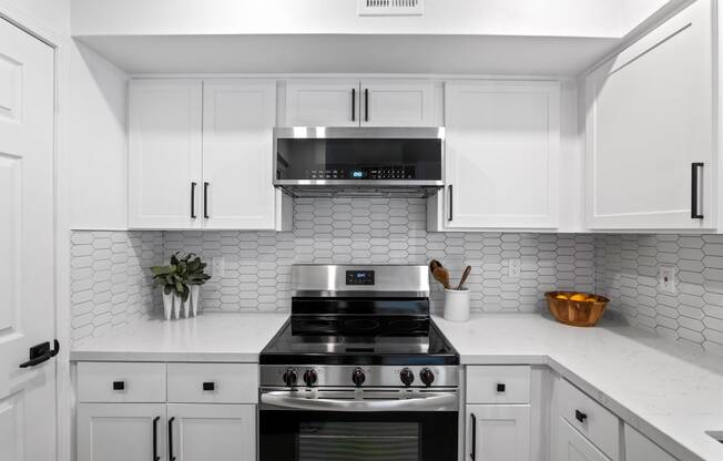 a white kitchen with a stove and white cabinets