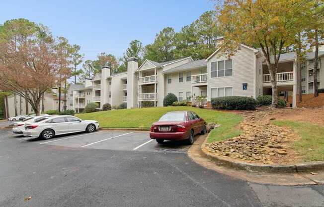 A parking lot with a red car and a silver car in front of a building.