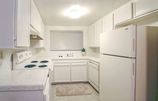 a small kitchen with white cabinets and a refrigerator