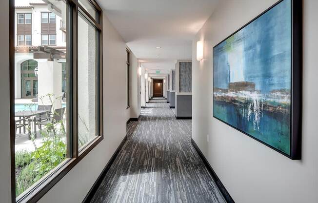 a hallway with large windows and a painting on the wall