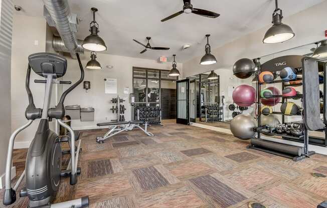 a gym with exercise equipment and weights on the floor and a wall of mirrors
