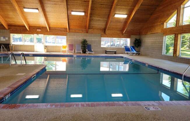 a swimming pool in a building with a wooden ceiling and a large window