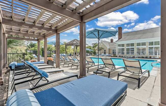 the pool is under a covered patio with lounge chairs and umbrellas