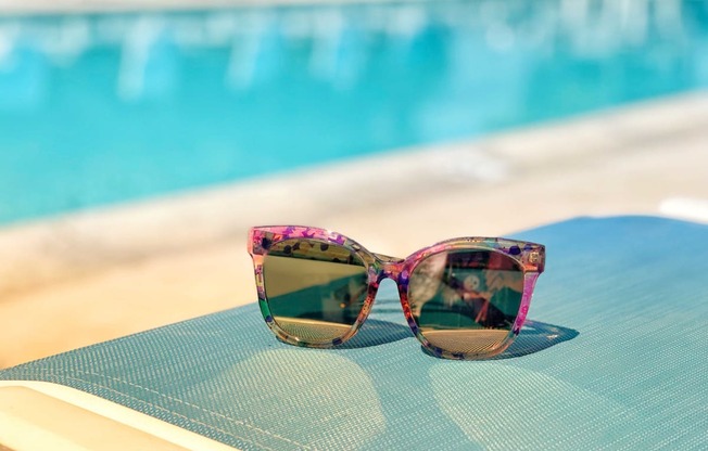 the sunglasses on the background of a blue swimming pool