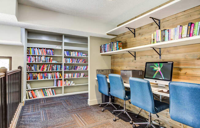 a library with a computer desk and three blue chairs