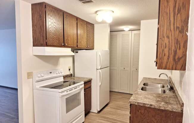 an empty kitchen with a stove refrigerator and sink