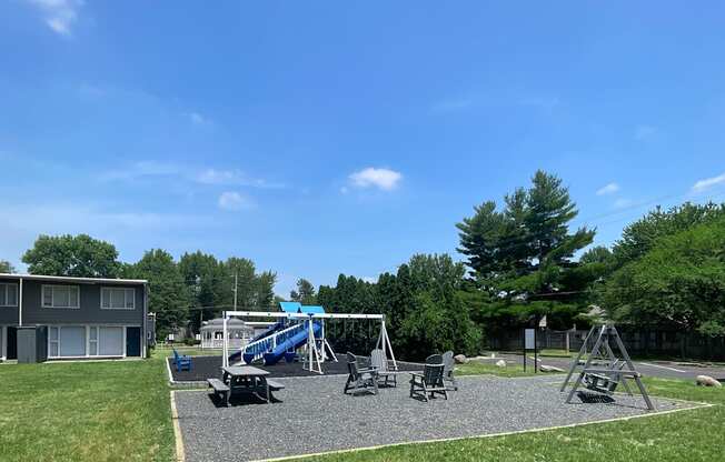 a playground with a swing set and chairs in a park