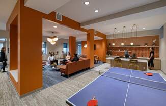 A ping pong table is in the middle of a room with people sitting on couches.