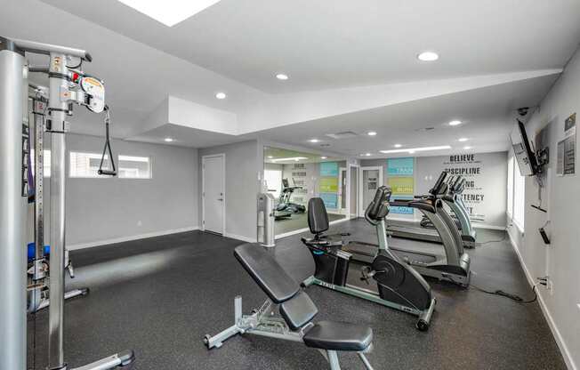 A gym with a row of treadmills and a weight machine.