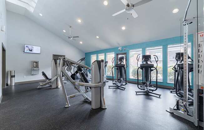 A gym with a variety of equipment including weights and a television.