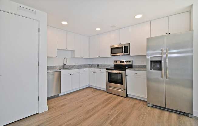 a white kitchen with stainless steel appliances and white cabinets