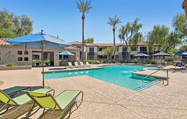 A pool surrounded by chairs and umbrellas with a building in the background.