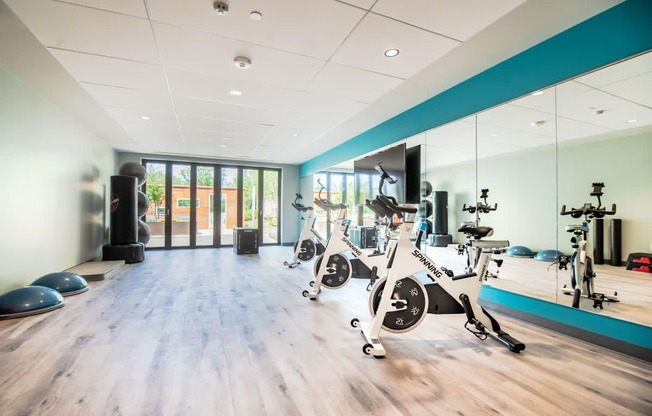 a gym with exercise bikes and weights on a wooden floor