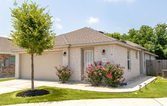 a white brick house with a tree in the front yard