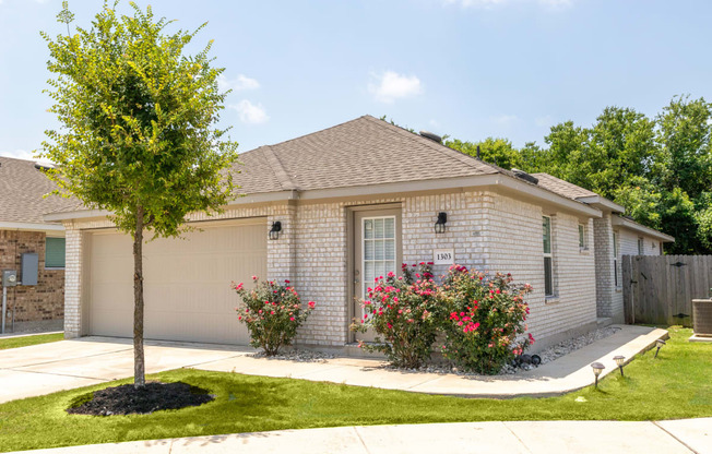 a white brick house with a tree in the front yard