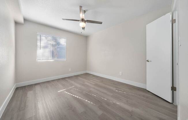 A room with a ceiling fan and a window with blinds.