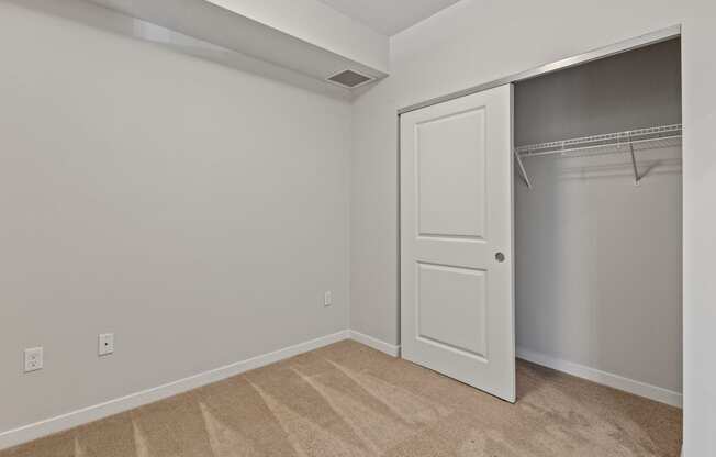 an empty bedroom with a closet and a white door