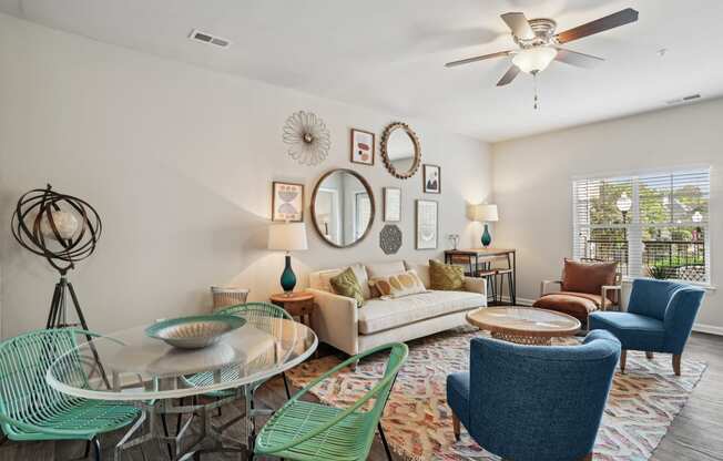 a living room with a ceiling fan and a round glass table