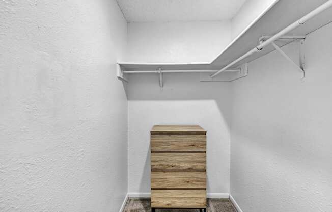 room with white walls and a wooden chest of drawers in the corner