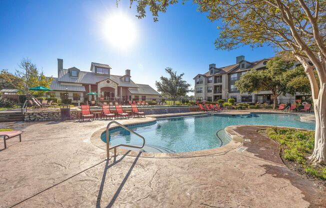 a resort style pool with chairs and a building in the background at The Fairways at Star Ranch, Hutto, TX, 78634