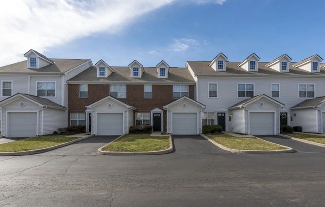 a row of houses with white roofs on a street at Traditions at Slate Ridge, Reynoldsburg, OH