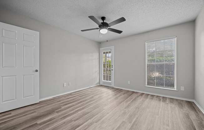 an empty living room with a ceiling fan and a window